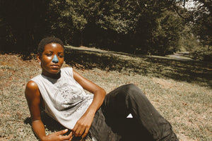 Girl sitting on grass using Noz reef safe SPF sunscreen that's safe for body and face